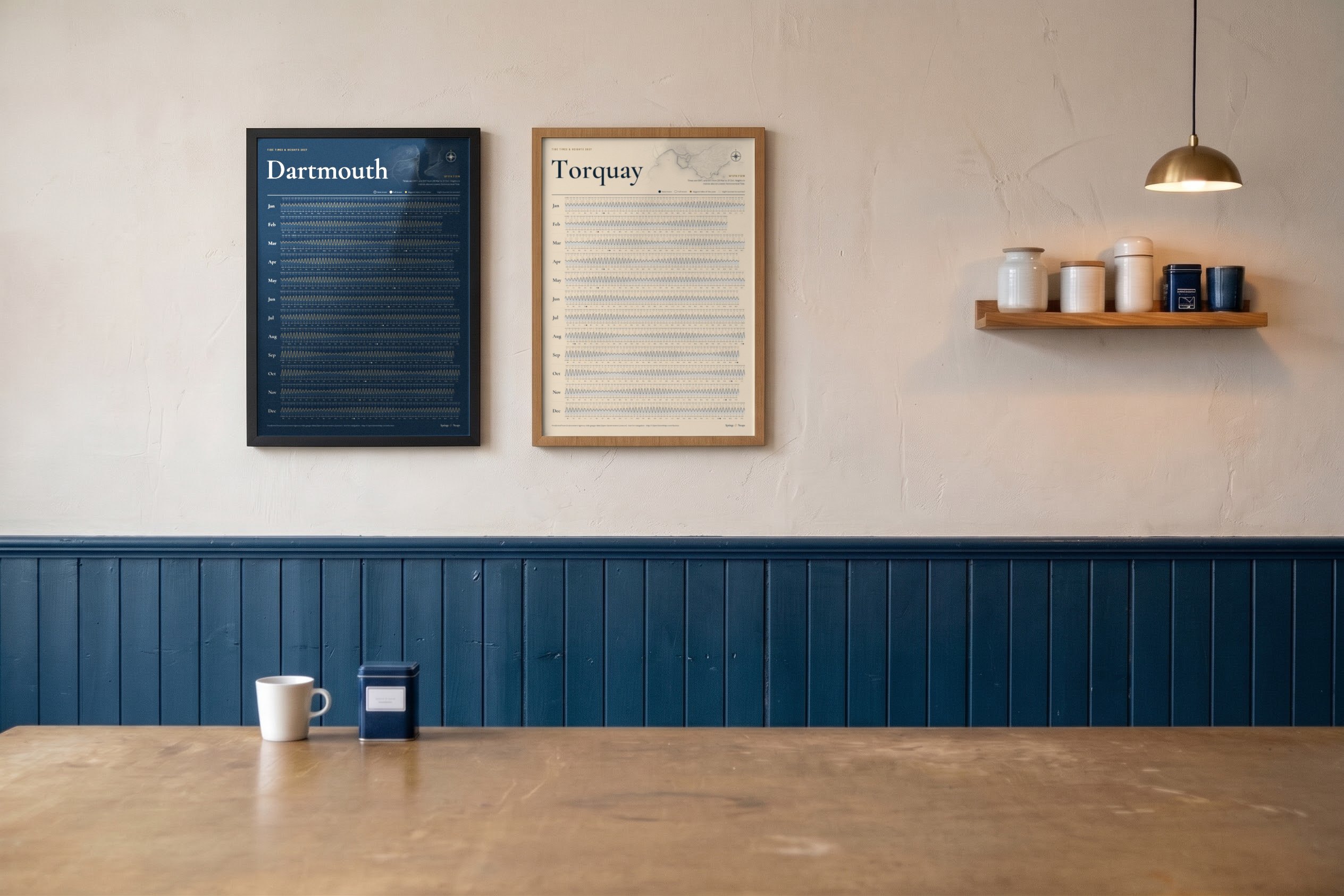 Two framed tide posters, Dartmouth and Torquay, on a café wall